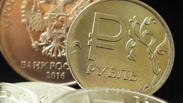 Монета номиналом один рубль с символикой Российского рубля. На дальнем плане - герб Российской Федерации на монете номиналом пять рублей РФ.