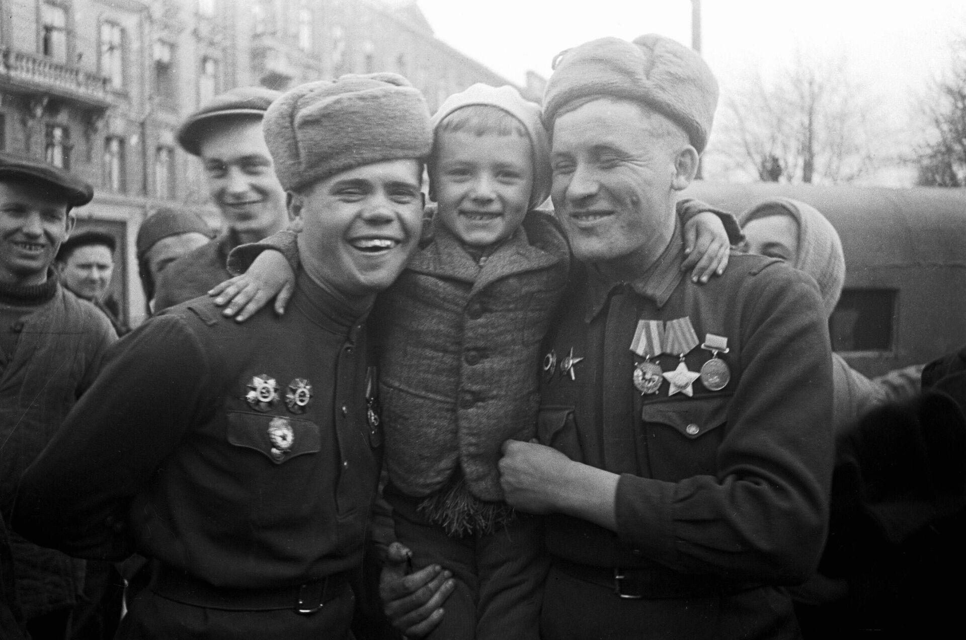 Советские воины-орденоносцы, участники боев за освобождение Одессы держат на плечах юного одессита. На снимке - военнослужащие отдельной армейской разведывательной роты 6-й армии 3-го Украинского фронта: разведчик ефрейтор Михаил Сысоев (справа) и командир разведывательного взвода лейтенант Андрей Васильков (слева) - РИА Новости, 1920, 21.05.2025