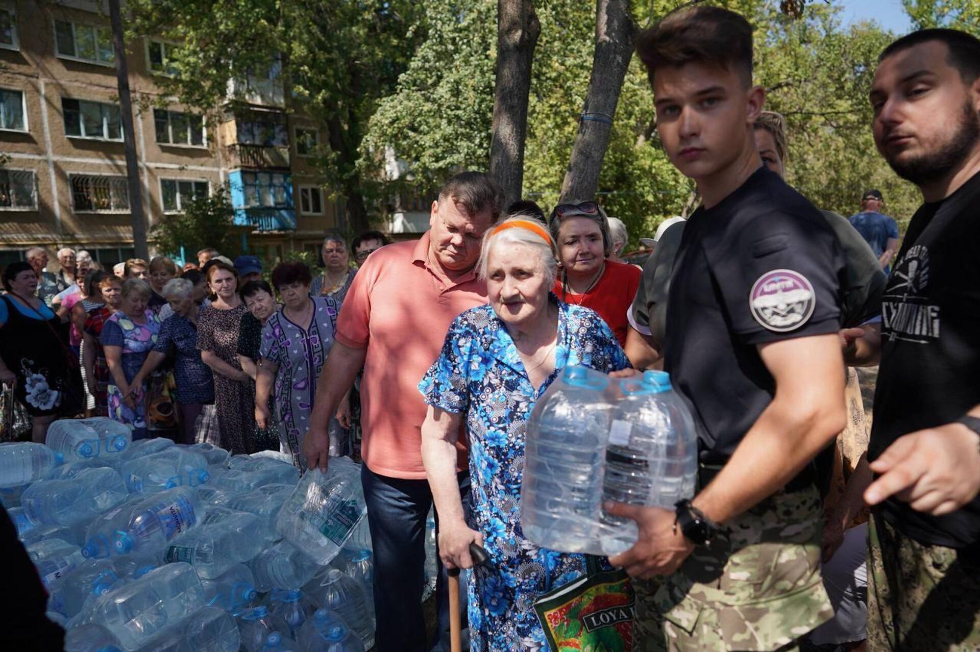 Волонтеры общественной организации Общество. Будущее раздают воду жителям ДНР - РИА Новости, 1920, 21.08.2025