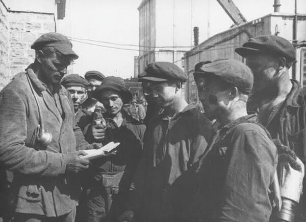 Знатный забойщик Никита Изотов инструктирует и дает задание членам своей бригады перед спуском на работу в шахту. 1934 год