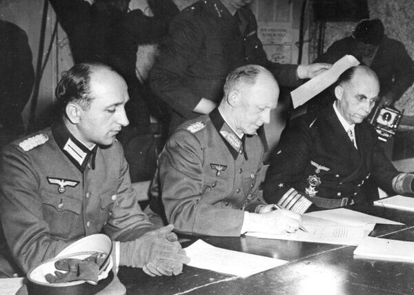 Генерал-полковник Альфред Йодль подписывает капитуляцию Германии в Реймсе, 7 мая 1945 года. Справа - гросс-адмирал Ганс-Георг фон Фридебург, слева - адъютант Йодля майор Вильгельм Оксениус