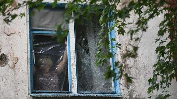 Женщина затягивает полиэтиленовой пленкой окно, разбитое в результате обстрелов ВСУ Донецка Женщина затягивает полиэтиленовой пленкой окно, разбитое в результате обстрелов ВСУ Донецка
