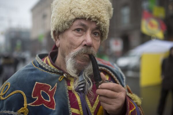 Мужчина в национальном костюме курит трубку на площади Независимости в Киеве